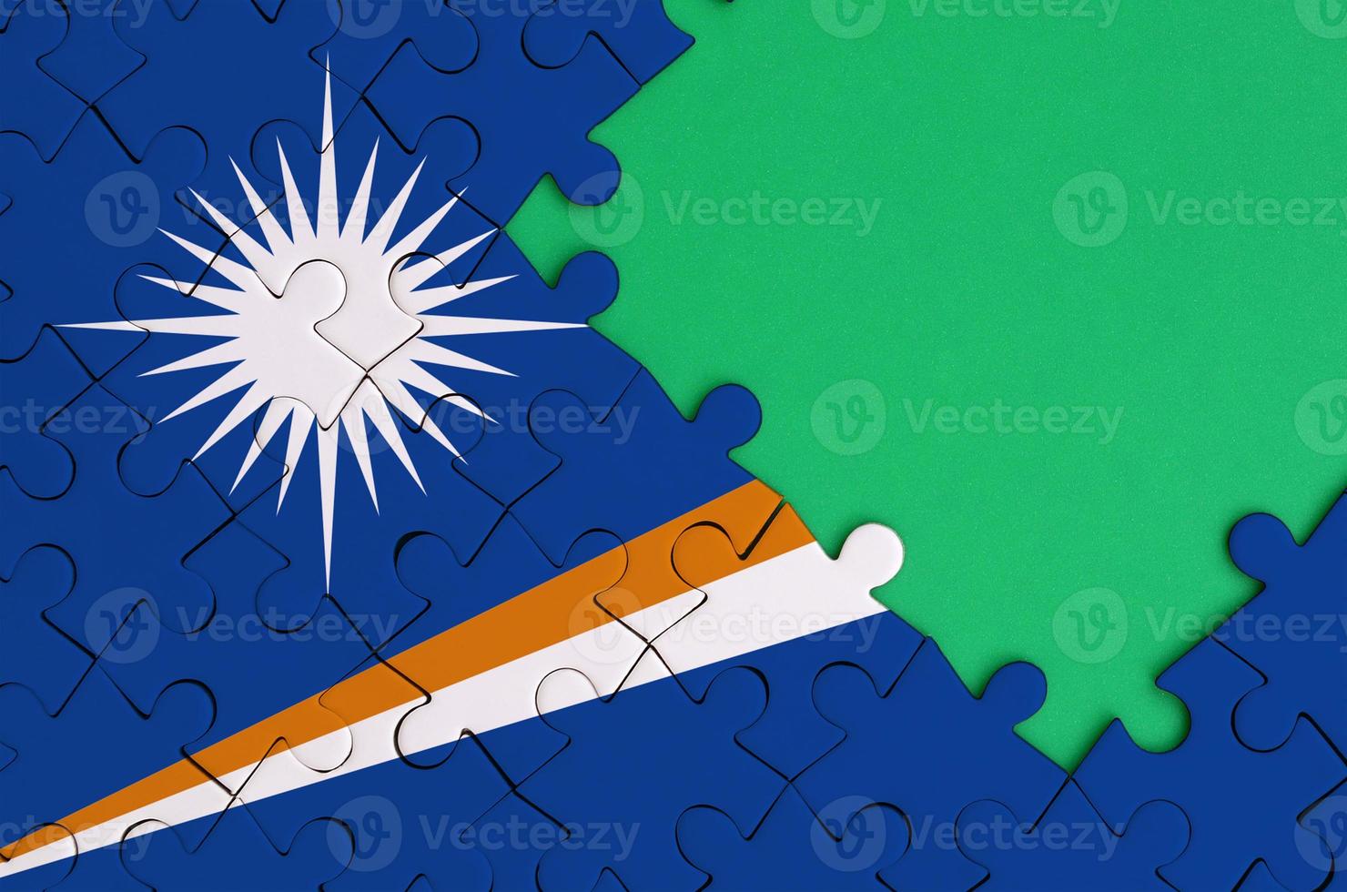 Marshall Islands flag  is depicted on a completed jigsaw puzzle with free green copy space on the right side photo
