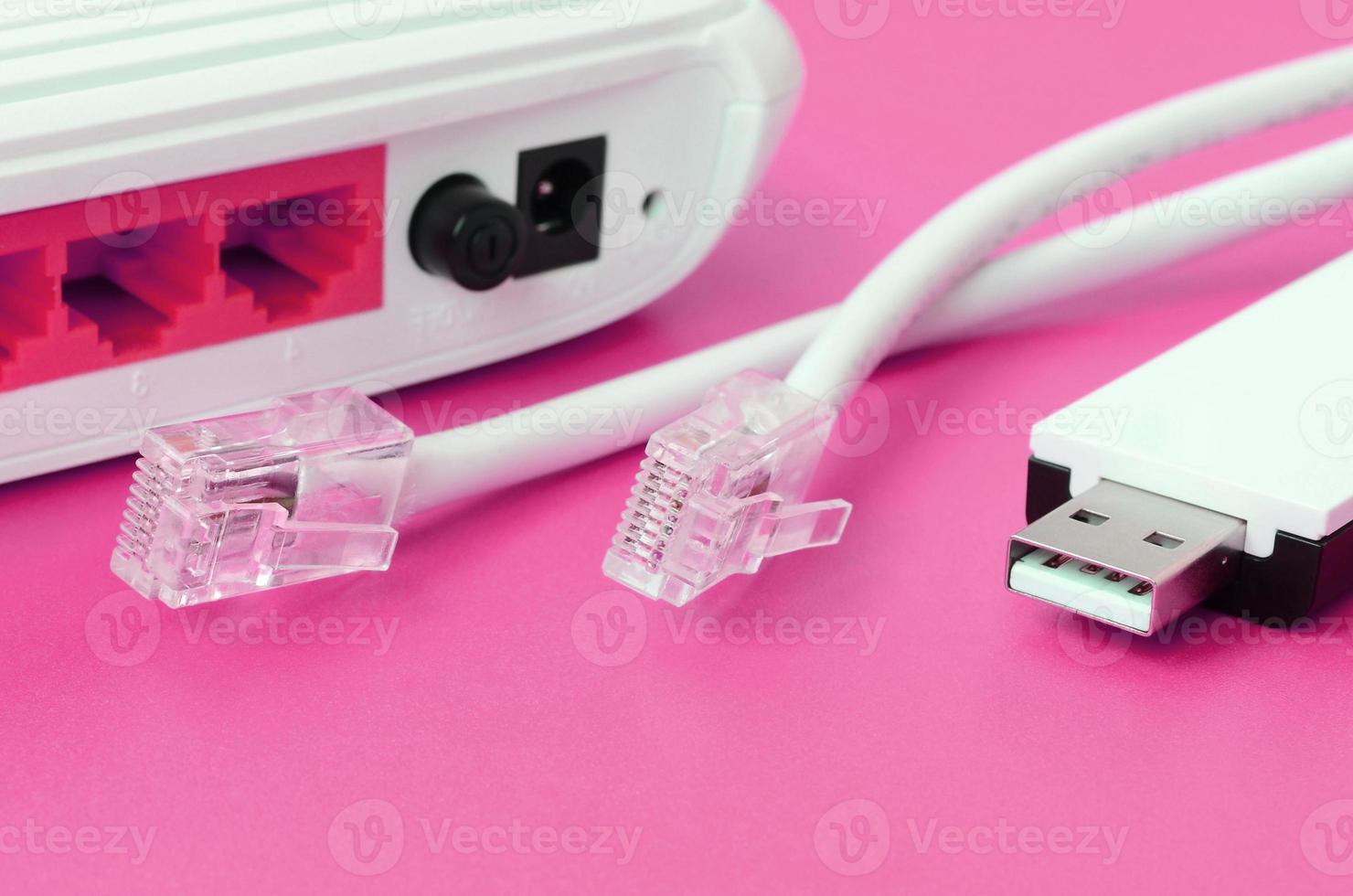 Internet router, portable USB wi-fi adapter and internet cable plugs lie on a bright pink background. Items required for internet photo