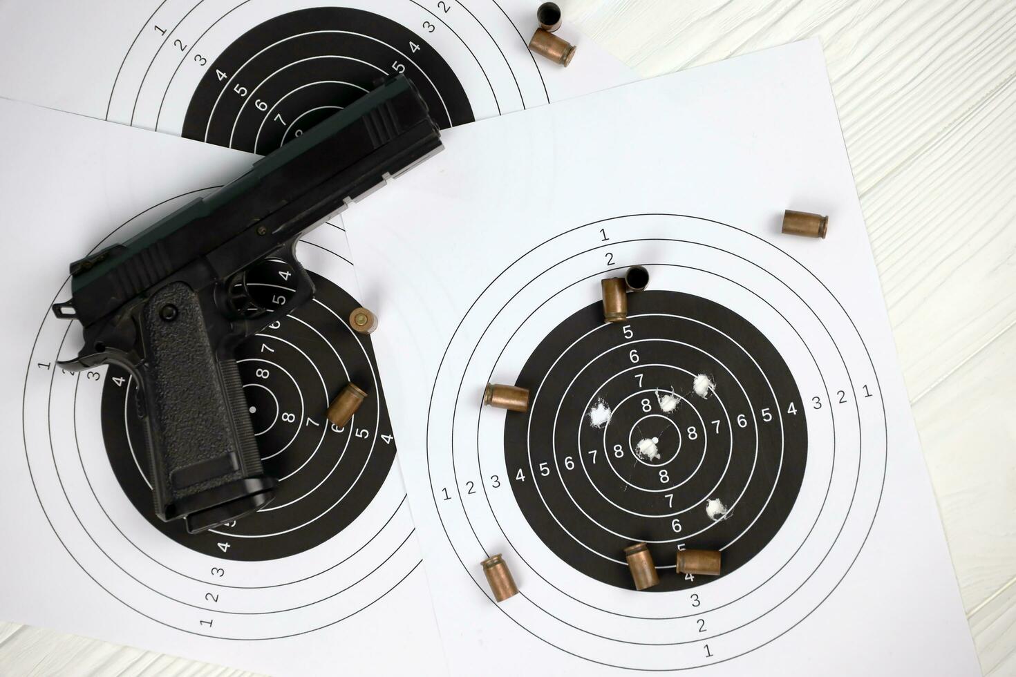 Gun and many bullets shooting targets on white table in shooting range polygon. Training for aiming and shooting photo