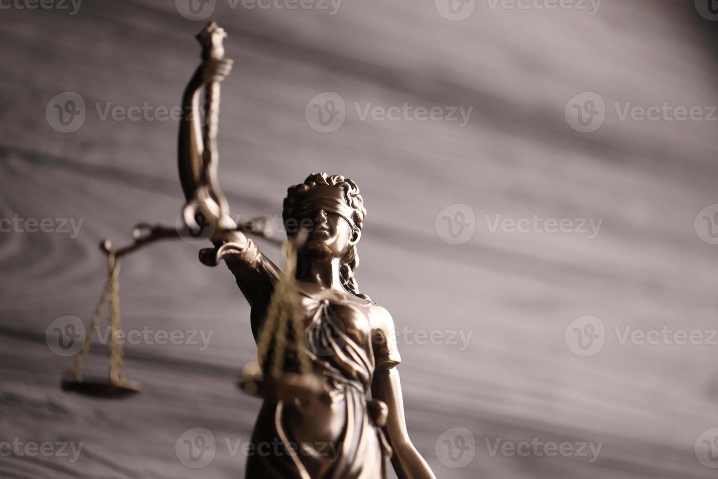 The Statue of Justice - lady justice or justitia the Roman goddess of Justice. Statue on black wooden wall. Concept of judicial trial, courtroom process and lawyers work photo