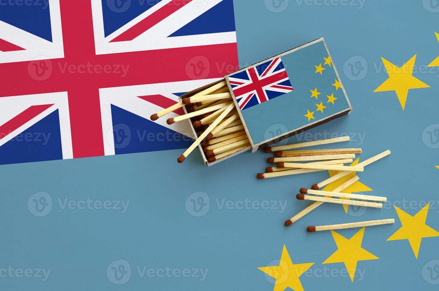 Tuvalu flag  is shown on an open matchbox, from which several matches fall and lies on a large flag photo
