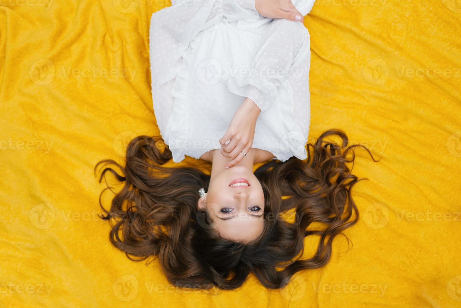 Top view of a happy white girl with a charming snow-white smile on a yellow background photo