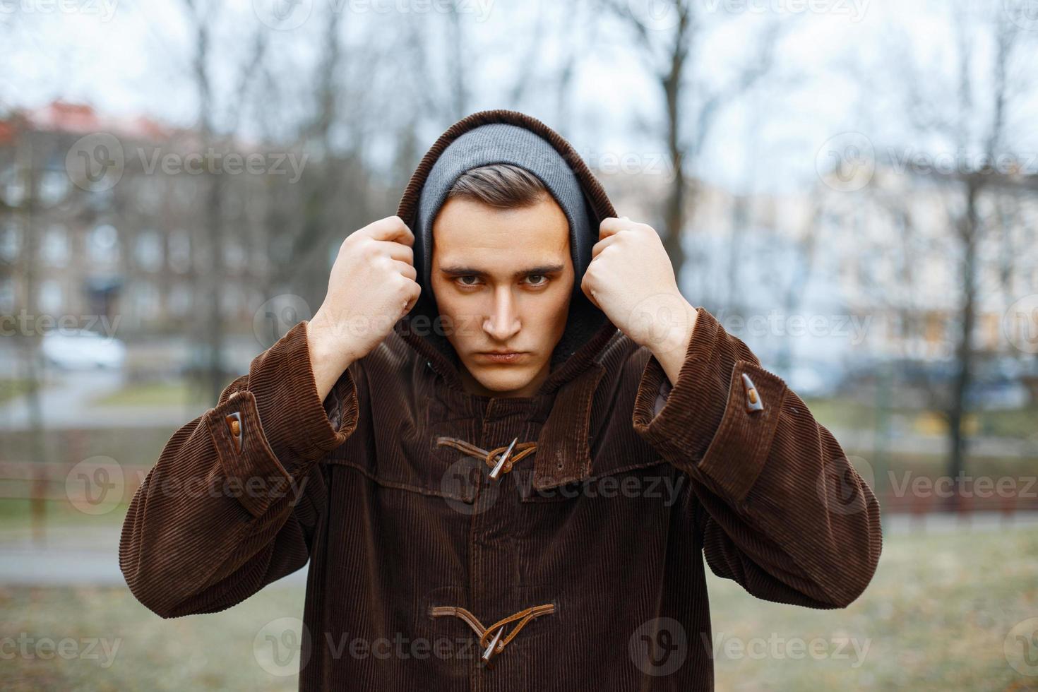 Angry man puts the hood on the background of autumn park photo