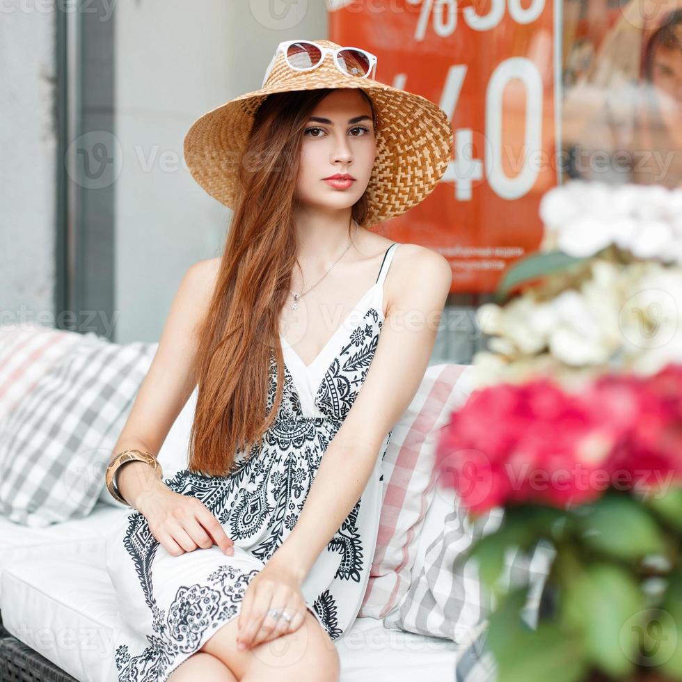 mujer elegante y hermosa con sombrero y gafas de sol descansando en el sofá después de ir de compras. foto