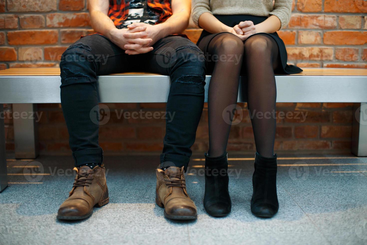 Fashionable stylish couple sitting on the bench. Legs close-up photo