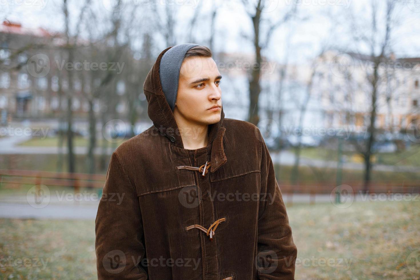 Young stylish guy in an old jacket and knit cap on a background of the autumn park photo