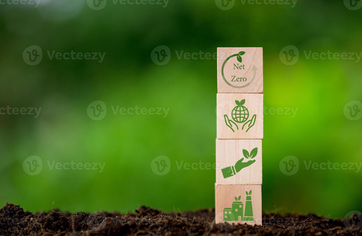 Net zero and carbon neutral concept. Net zero greenhouse gas emissions target. Climate neutral long term strategy. Wooden cubes with green net zero icon and green conserve icon on nature background. photo