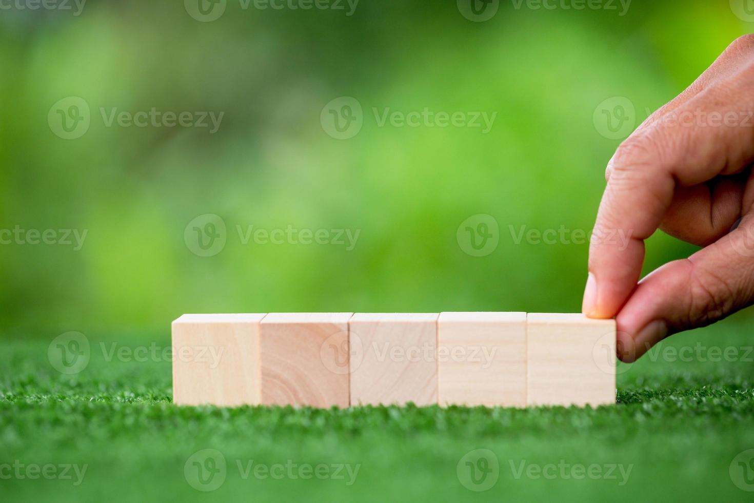 Stacking blank wooden cubes on green background with copy space for input wording and infographic icon. Empty brown wooden object block for symbol icon put technology, zero gravity, business concept. photo