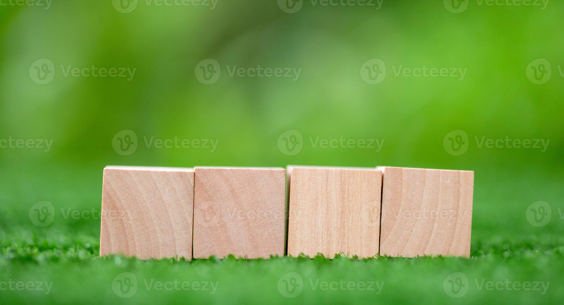 Stacking blank wooden cubes on green background with copy space for input wording and infographic icon. Empty brown wooden object block for symbol icon put technology, zero gravity, business concept. photo