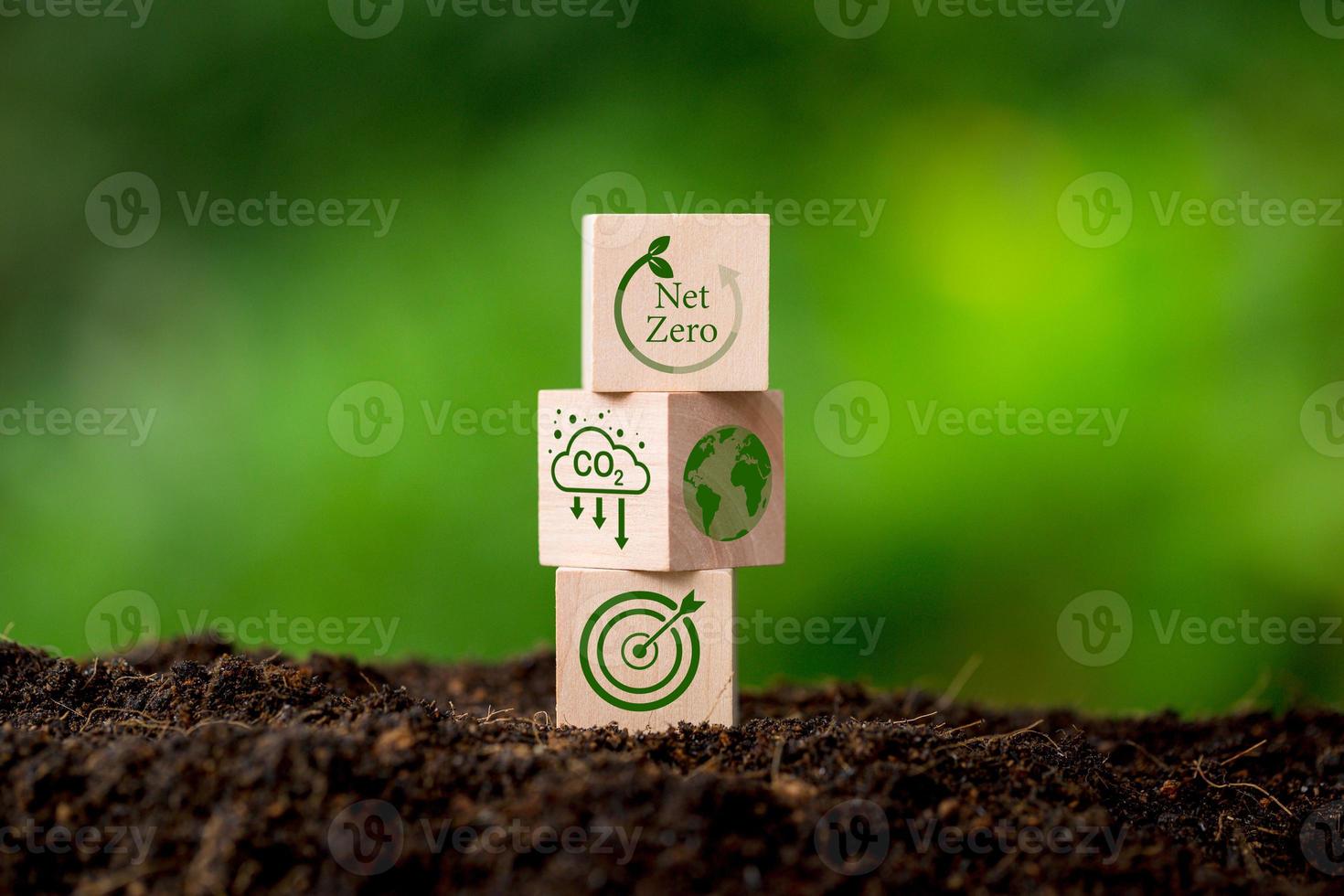 Net zero and carbon neutral concept. Net zero greenhouse gas emissions target. Climate neutral long term strategy. Wooden cubes with green net zero icon and green conserve icon on nature background. photo