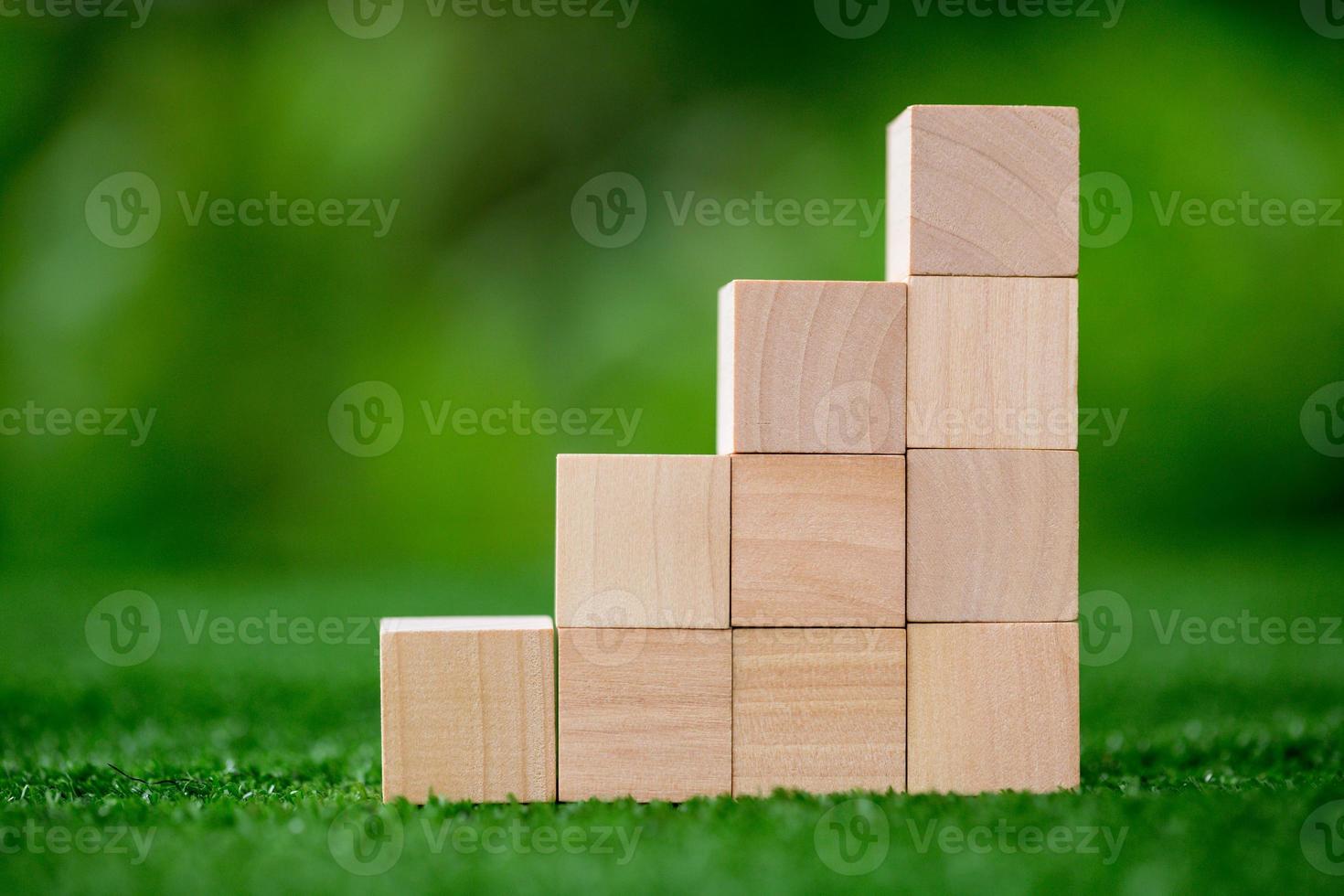Stacking blank wooden cubes on green background with copy space for input wording and infographic icon. Empty brown wooden object block for symbol icon put technology, zero gravity, business concept. photo