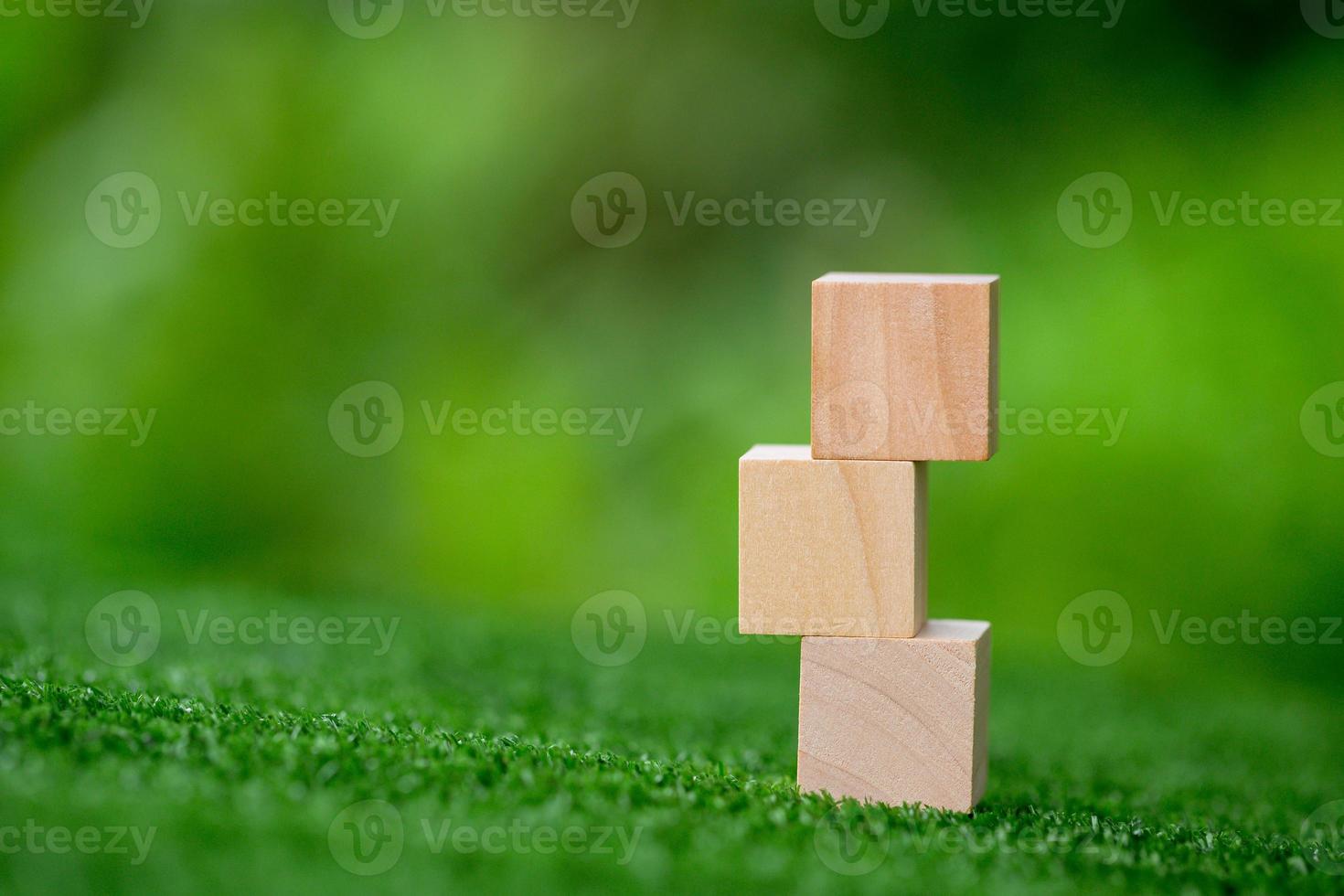 Stacking blank wooden cubes on green background with copy space for input wording and infographic icon. Empty brown wooden object block for symbol icon put technology, zero gravity, business concept. photo
