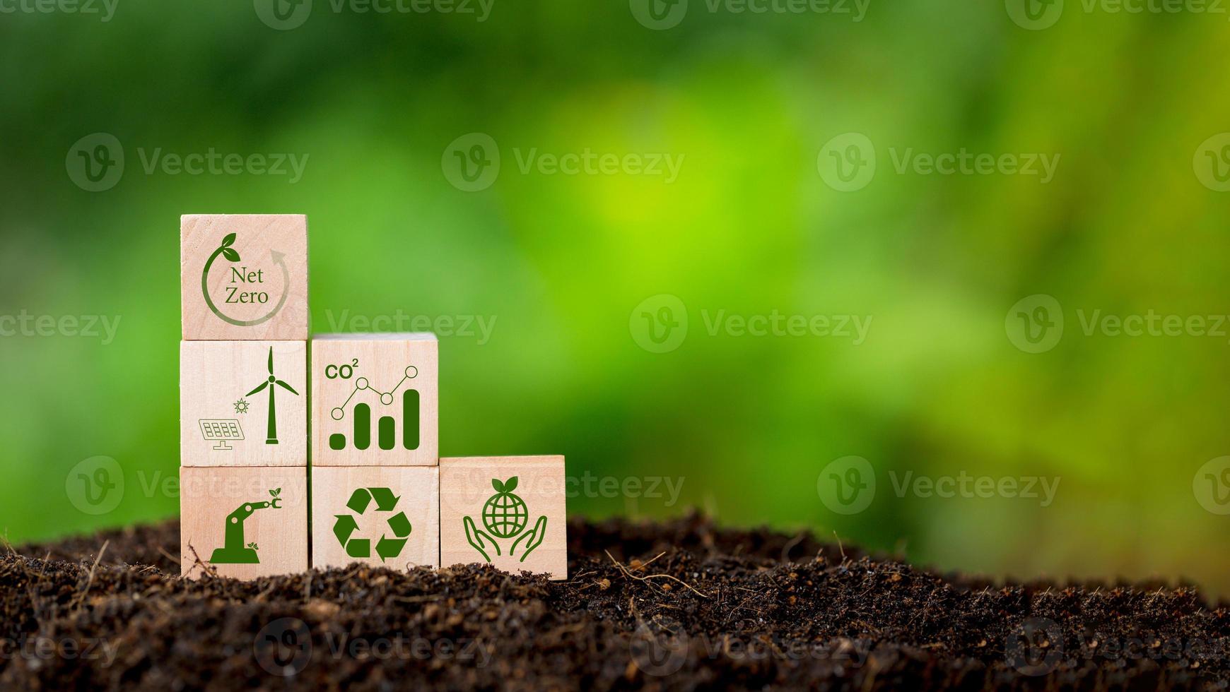 Net zero and carbon neutral concept. Net zero greenhouse gas emissions target. Climate neutral long term strategy. Wooden cubes with green net zero icon and green conserve icon on nature background. photo