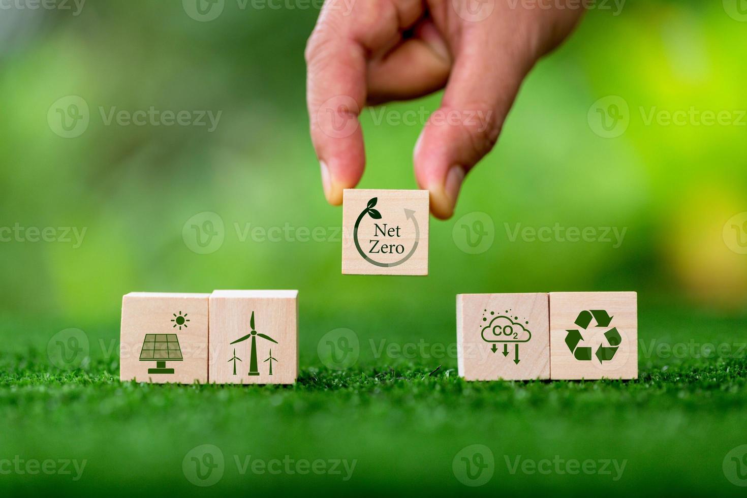 Net zero and carbon neutral concept. Net zero greenhouse gas emissions target. Climate neutral long term strategy. Wooden cubes with green net zero icon and green conserve icon on nature background. photo