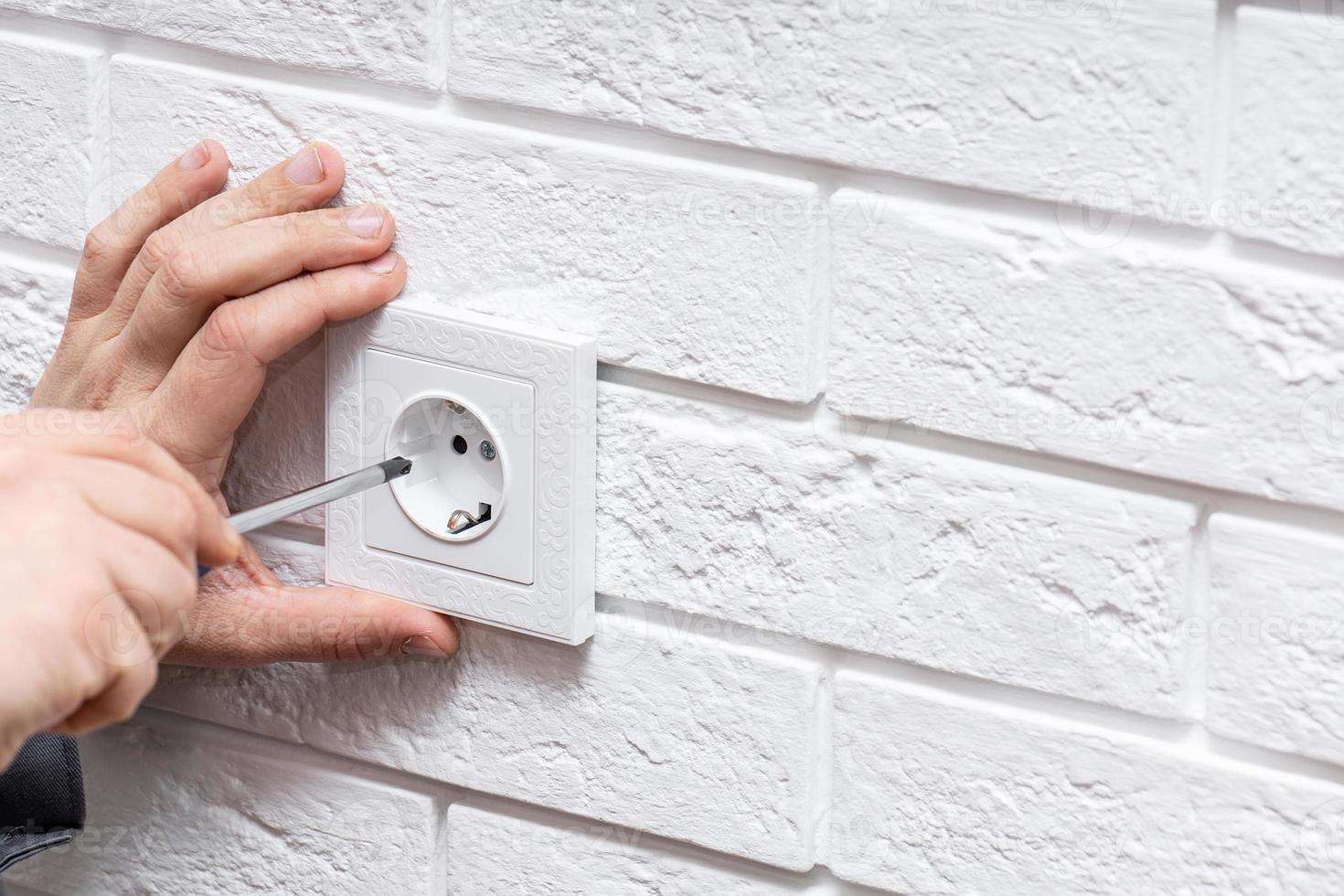 Electrician replacing socket in room. photo