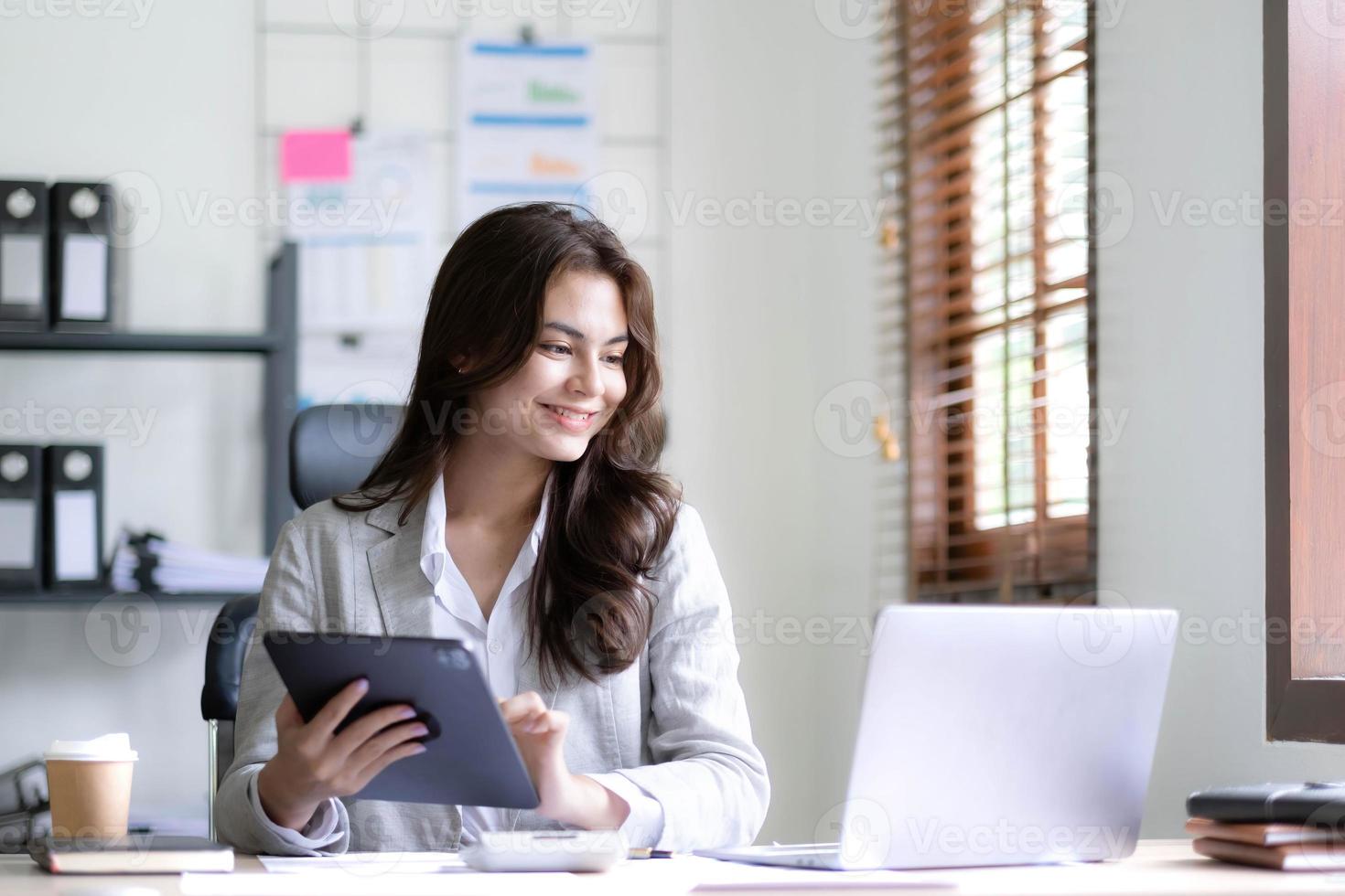 Asian Business woman using calculator and laptop for doing math finance on an office desk, tax, report, accounting, statistics, and analytical research concept photo