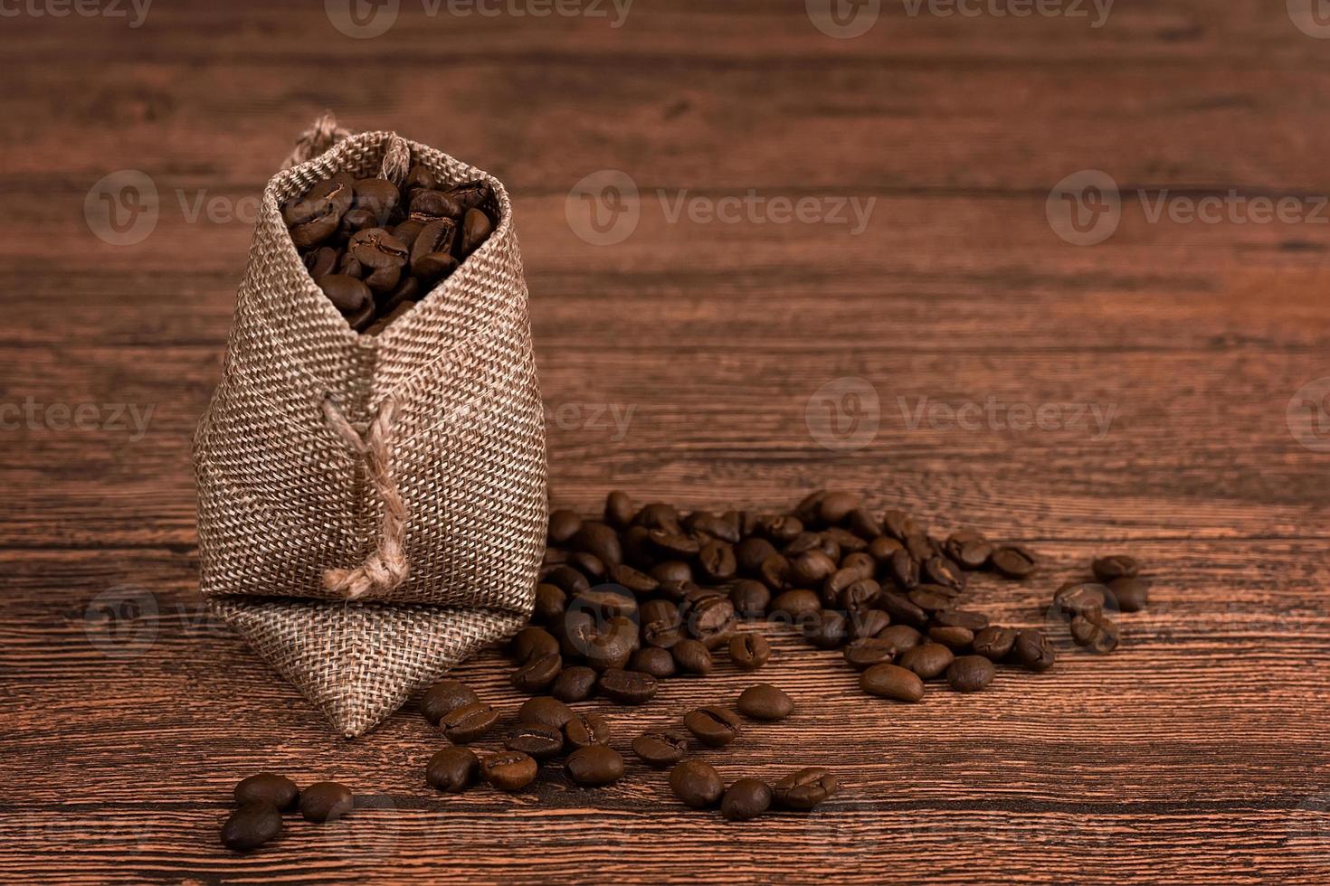 bolsa de embalaje de papel de café negro en la vista superior de la mesa de madera. concepto de endecha plana de frijoles derramados. espacio para texto. foto