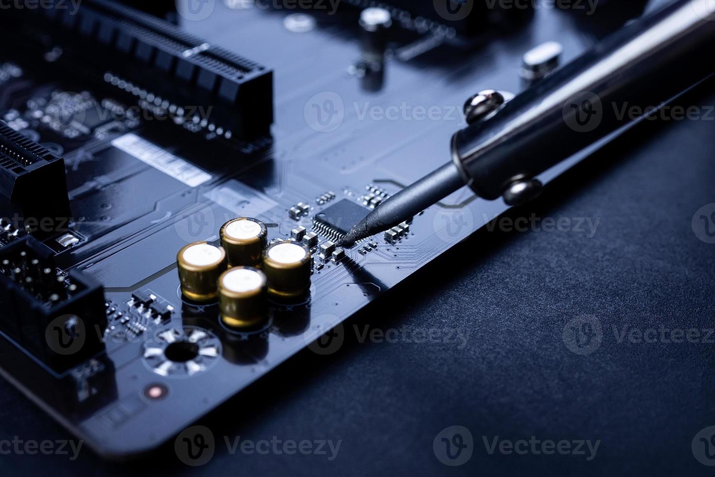 Repairman is soldering the motherboard of electronic device photo