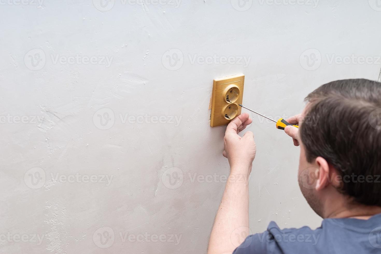 Electrician replacing socket in room photo