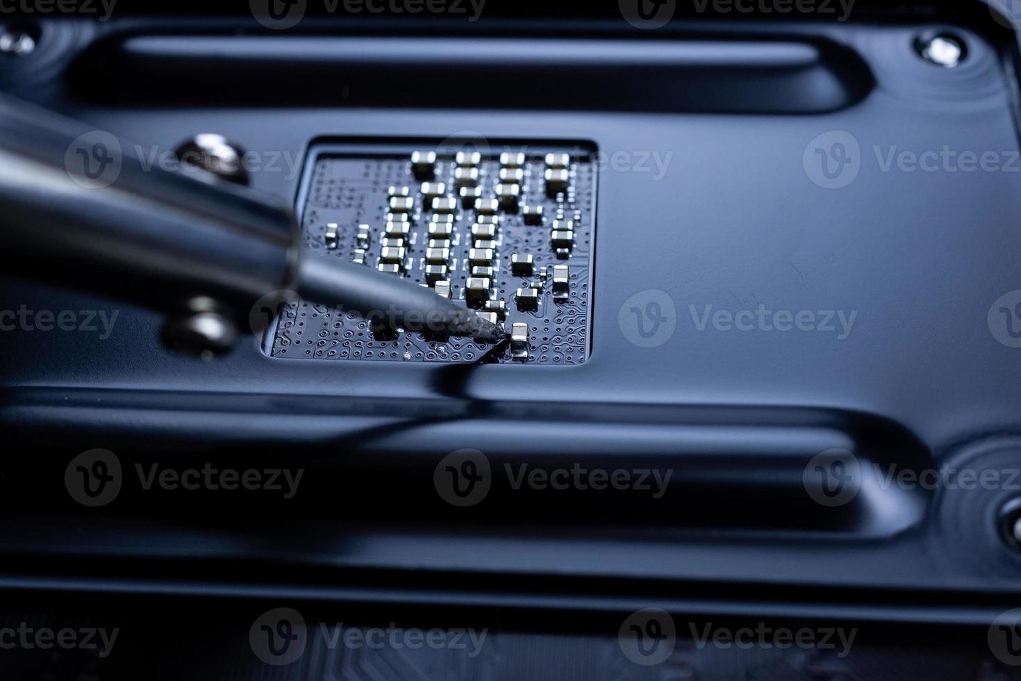 Repairman is soldering the motherboard of electronic device photo