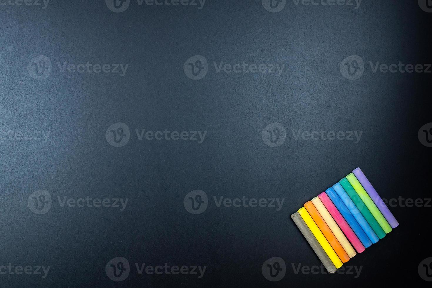 Multicoloured chalk on blackboard background photo