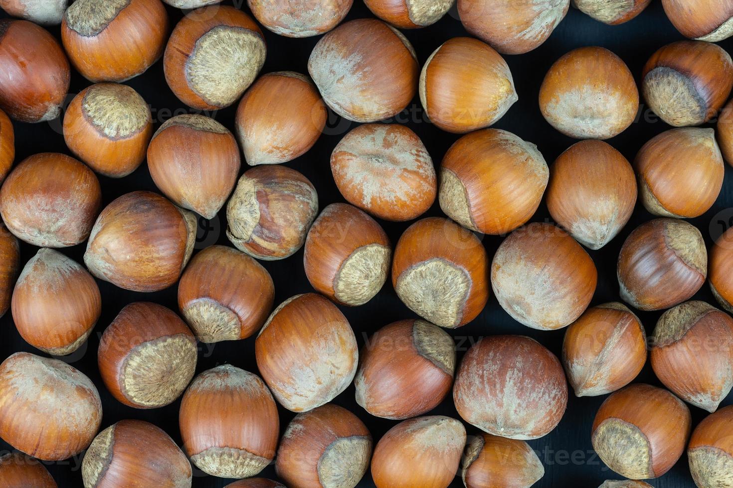Hazelnuts on a black background. Fresh hazelnut harvest is scattered on black table. photo