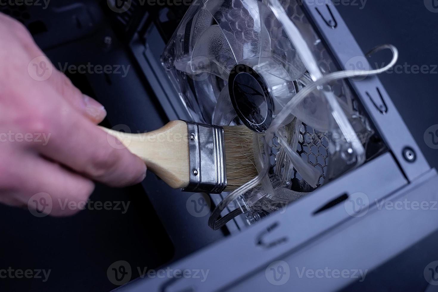 Cleaning a dirty computer fan with a brush photo