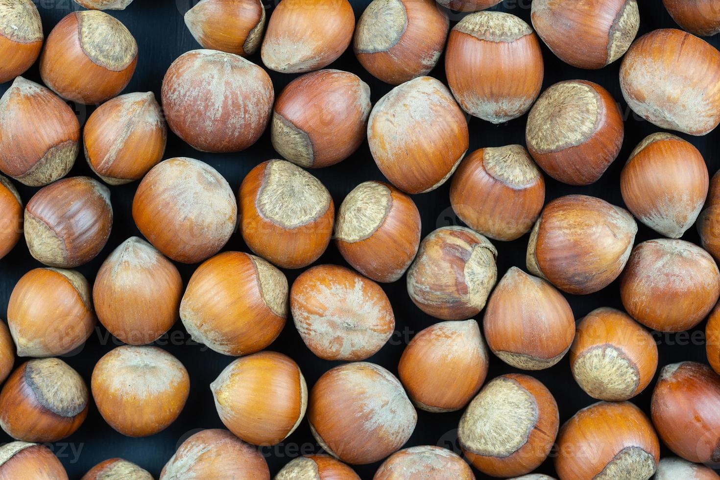 Hazelnuts on a black background. Fresh hazelnut harvest is scattered on black table. photo