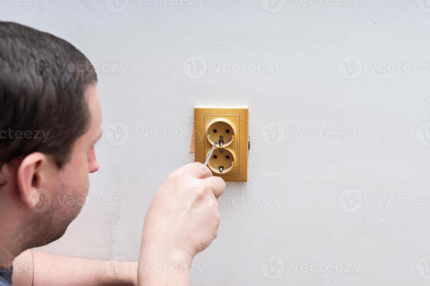 Electrician replacing socket in room photo