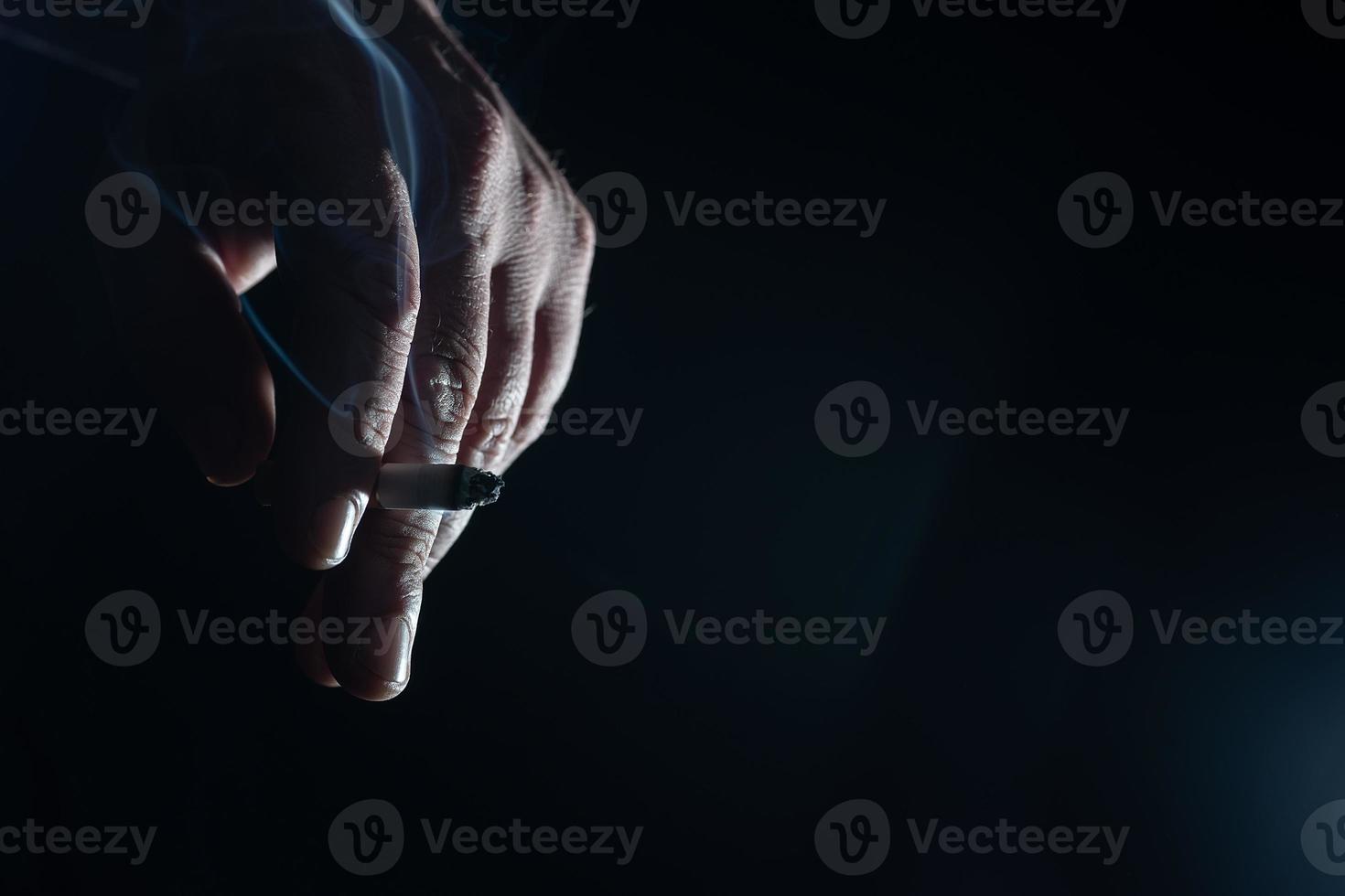 A Cropped of man hand holding cigarette black background photo