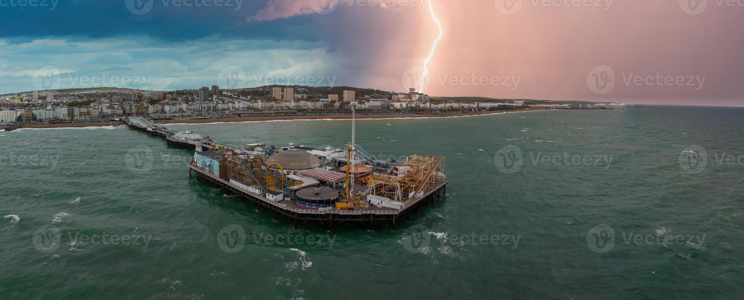 vista aérea del muelle del palacio de brighton, con el paseo marítimo detrás. toma aérea de la impresionante ciudad de brighton y hove con gaviotas volando durante tormentas eléctricas y relámpagos. foto