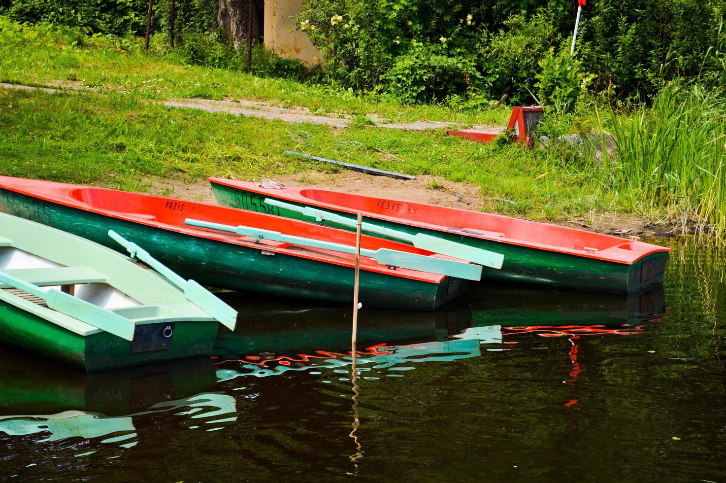 Beautiful wooden multicolored boats with oars on the beach for walks along the river, lake, sea, ocean in a nature park on the shore photo