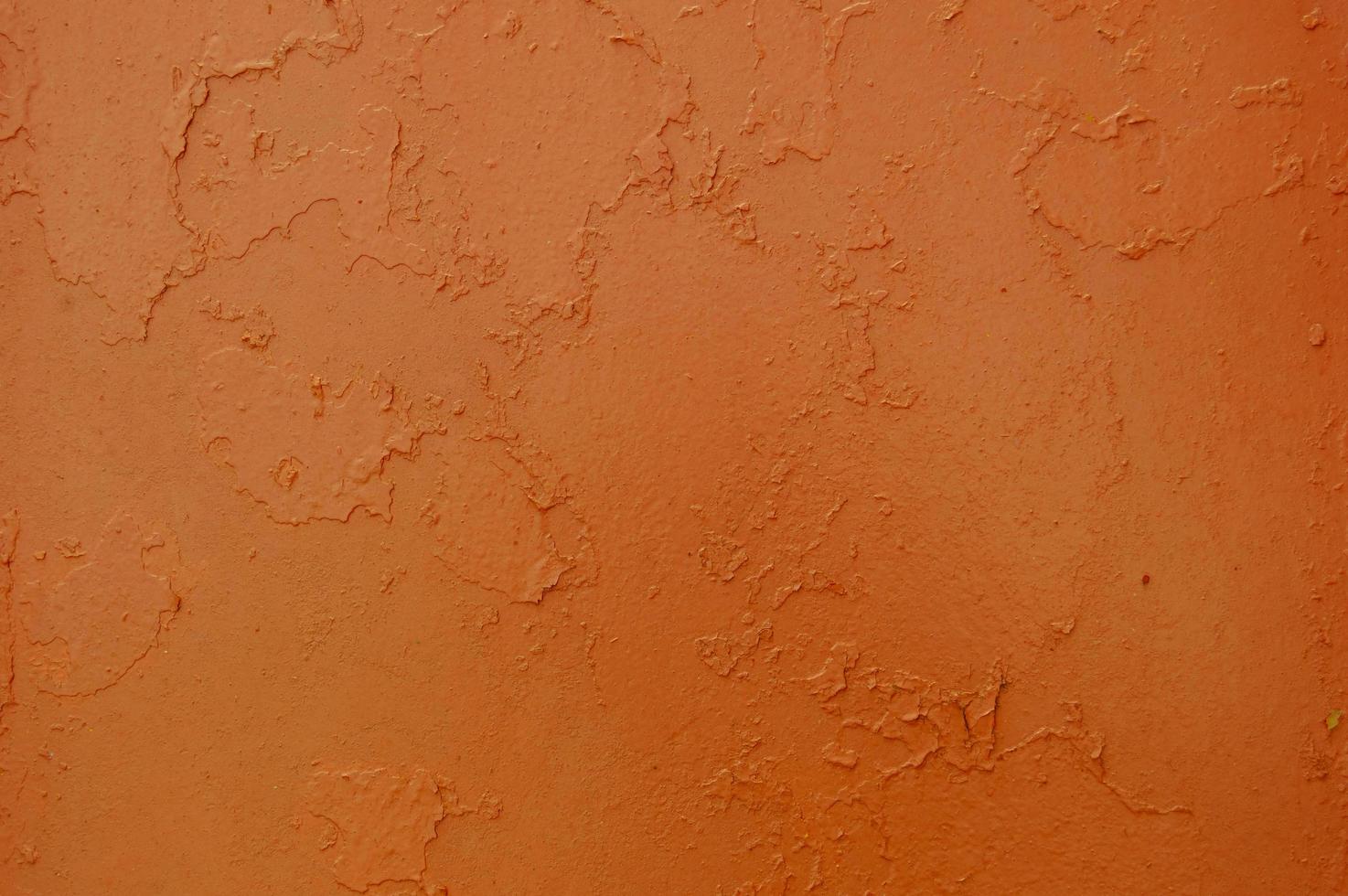Texture of iron metal painted bright orange with peeling paint of old battered scratched cracked ancient rusty metal sheet wall with corrosion. The background photo
