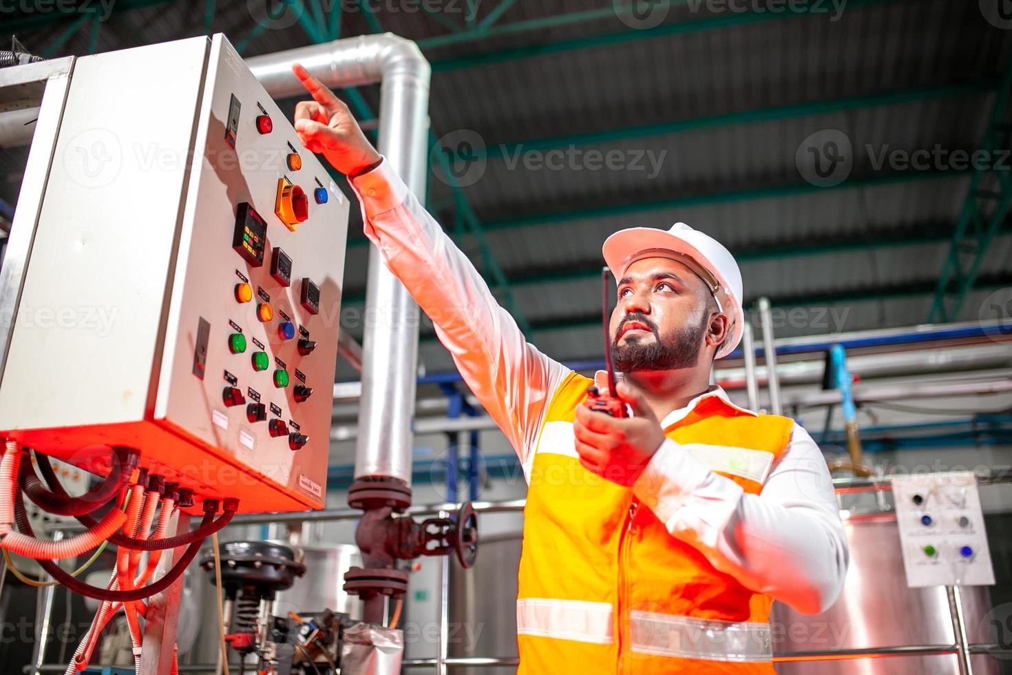 Professional engineers with helmets work to maintain industrial construction equipment, workers are inspecting or repairing machines  with radio. photo