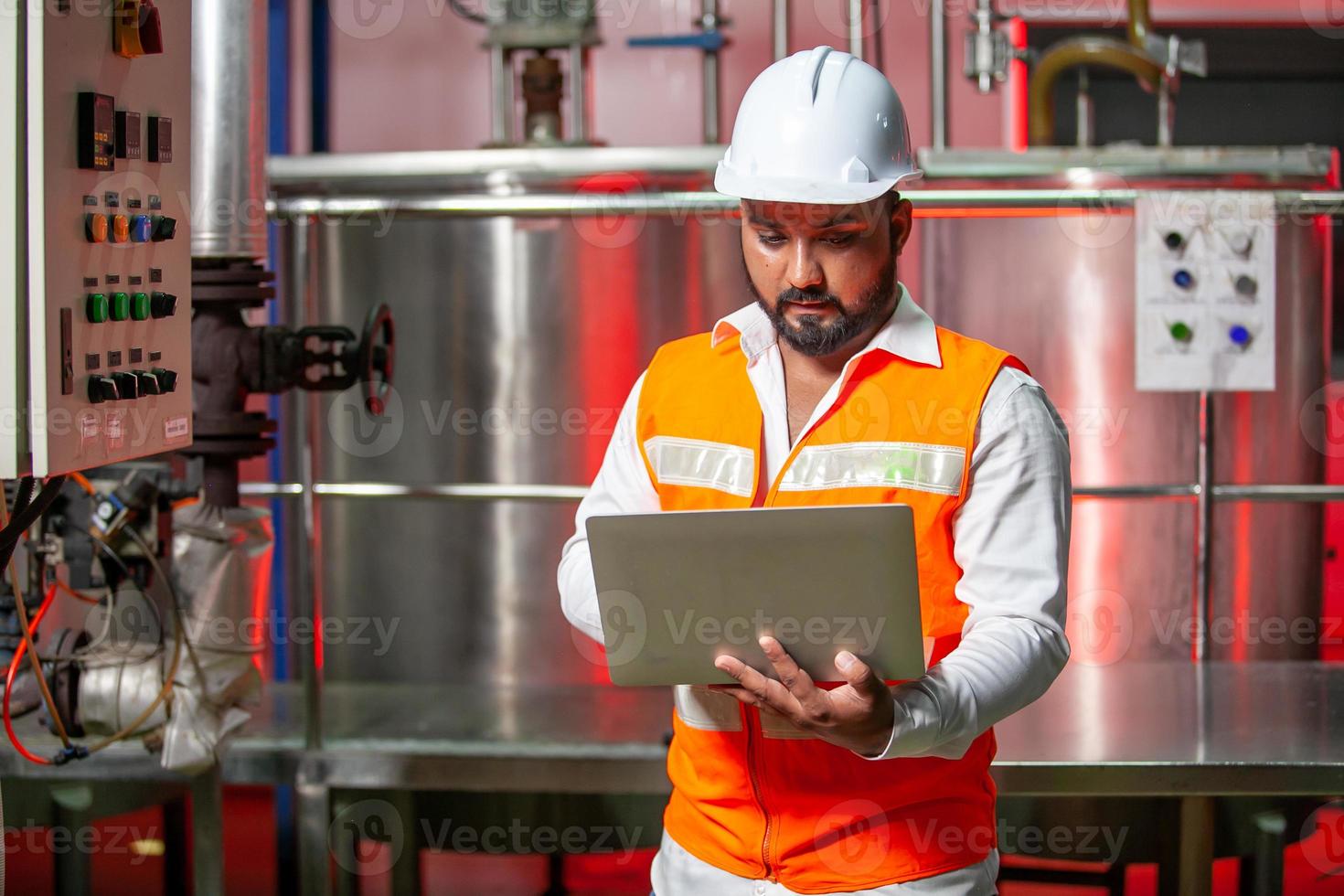 Professional engineers with helmets work to maintain industrial construction equipment, workers are inspecting or repairing machines  with laptop. photo