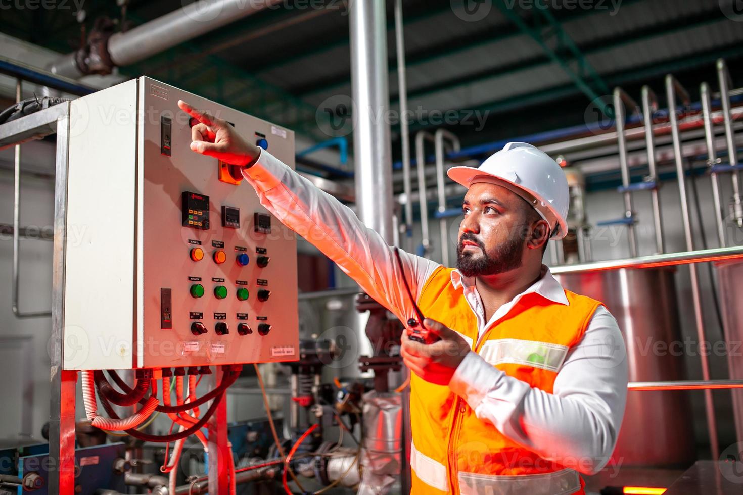 Professional engineers with helmets work to maintain industrial construction equipment, workers are inspecting or repairing machines  with radio. photo