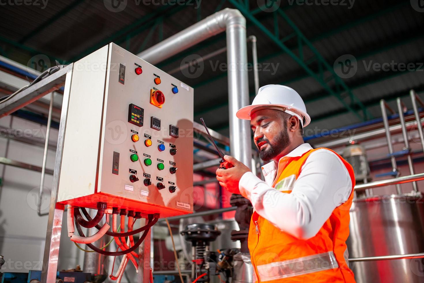 Professional engineers with helmets work to maintain industrial construction equipment, workers are inspecting or repairing machines  with radio. photo