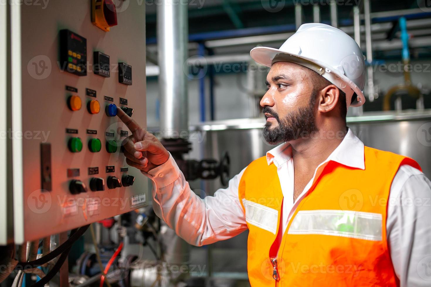 Asian engineer worker wearing safety uniform control operating  machine and turn on switch in industry factory. photo