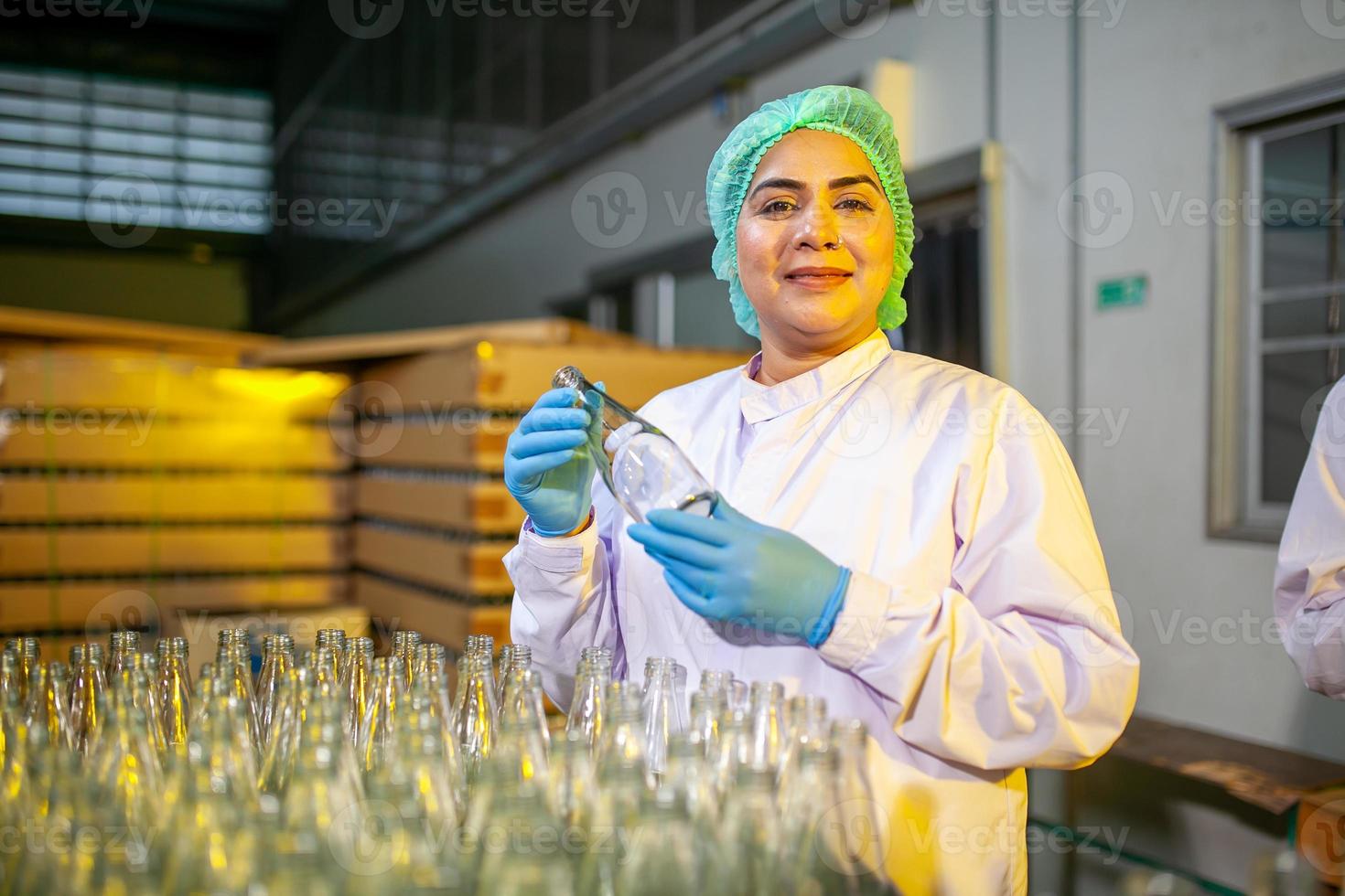 Asian workers with clipboard is checking product bottles of fruit juice on the production line in the beverage factory. Manufacturer checks quality of food industry. photo