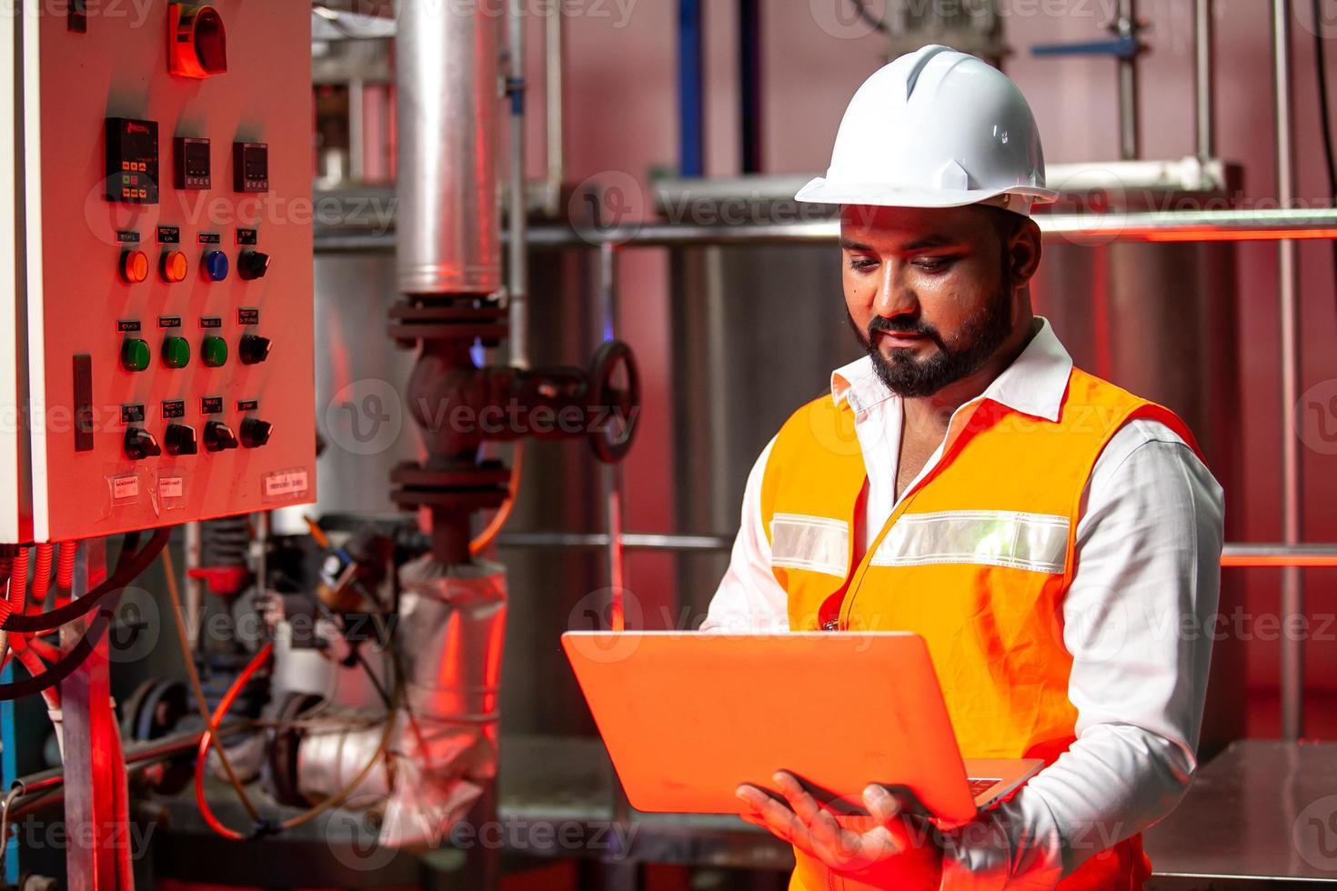 ingenieros profesionales con cascos trabajan para mantener equipos de construcción industrial, los trabajadores están inspeccionando o reparando máquinas con laptop. foto