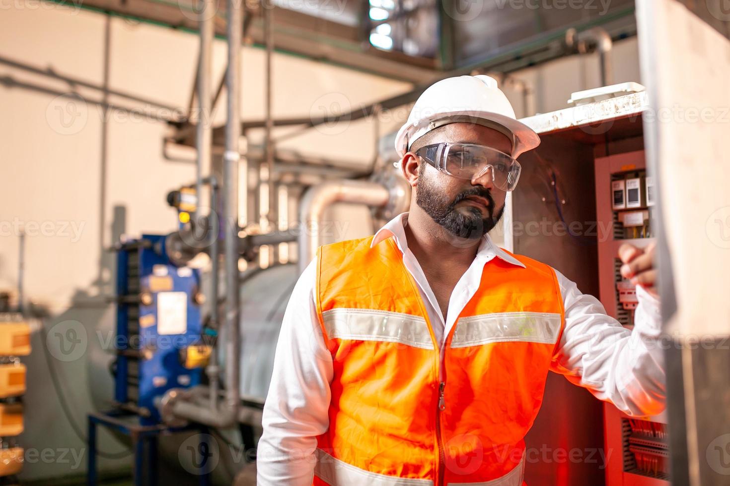 Asian engineer worker wearing safety uniform control operating  machine and turn on switch in industry factory. photo