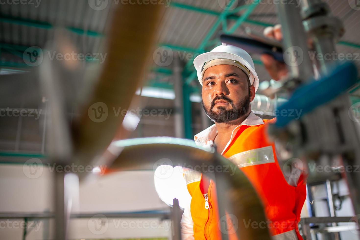 ingeniero técnico profesional con casco de seguridad que trabaja para el mantenimiento de equipos de construcción en una fábrica industrial, el trabajador está revisando o reparando la máquina. foto