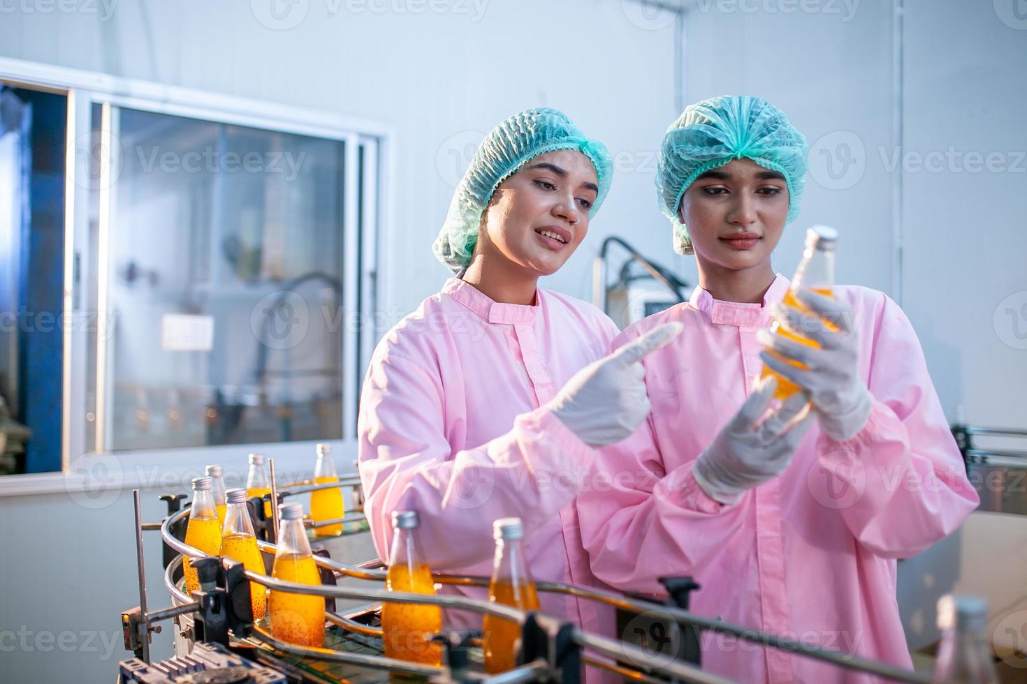 Asian woman worker is checking product bottles of fruit juice on the production line in the beverage factory. Manufacturer checks quality of food industry. photo