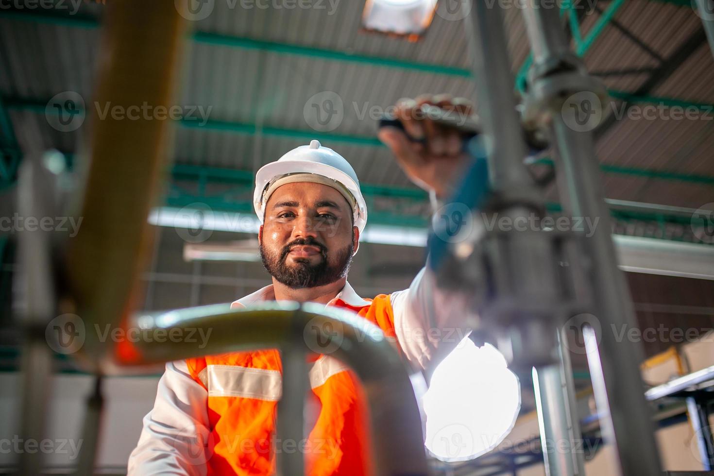 professional technician engineer with safety hard hat working to maintenance construction equipment in industrial factory, worker is checking or repair the machine. photo