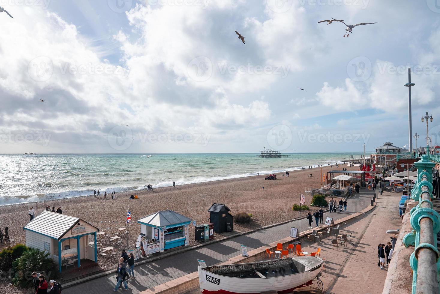 People walking down the promenade near the beach in Brighton. photo