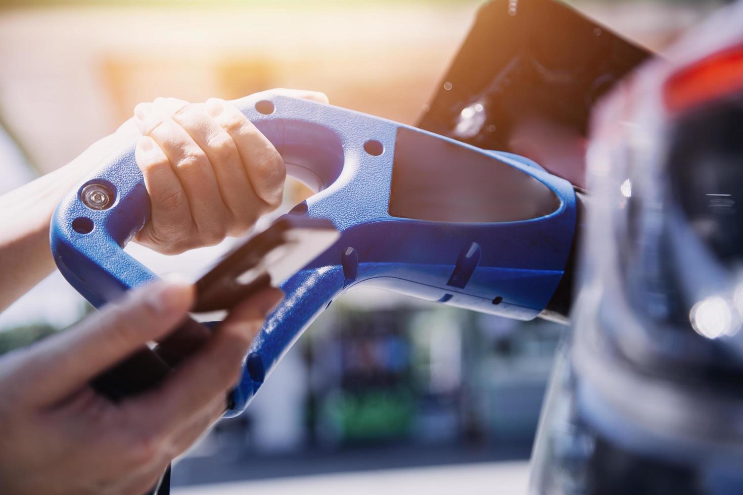 Hand plugging in a charger in an electric car socket.Electric car or ev is charging at station photo