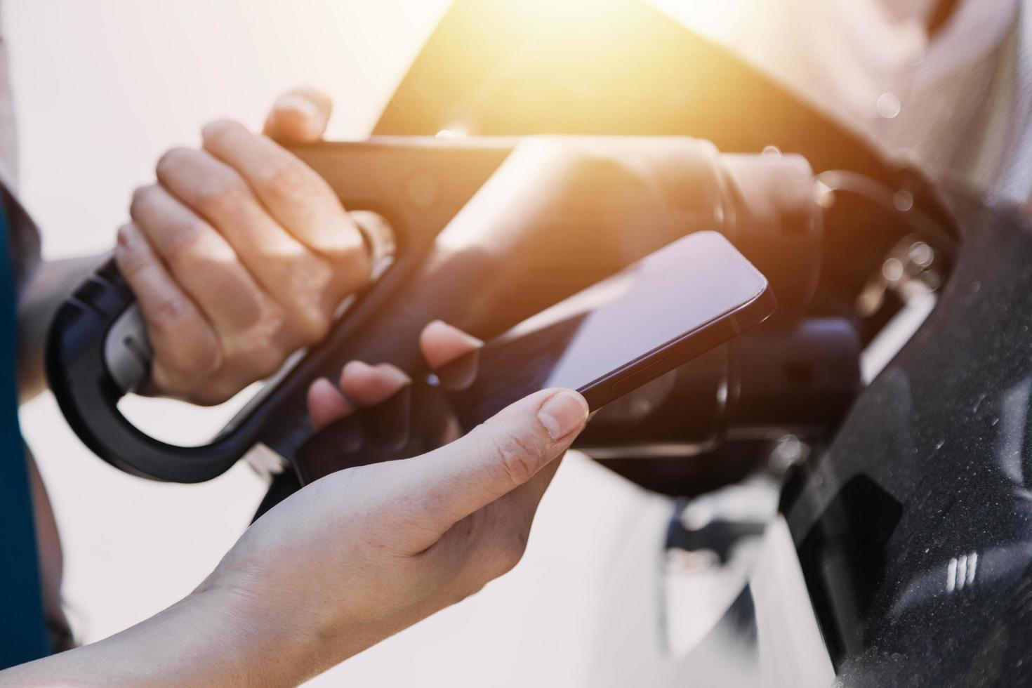 Hand plugging in a charger in an electric car socket.Electric car or ev is charging at station photo