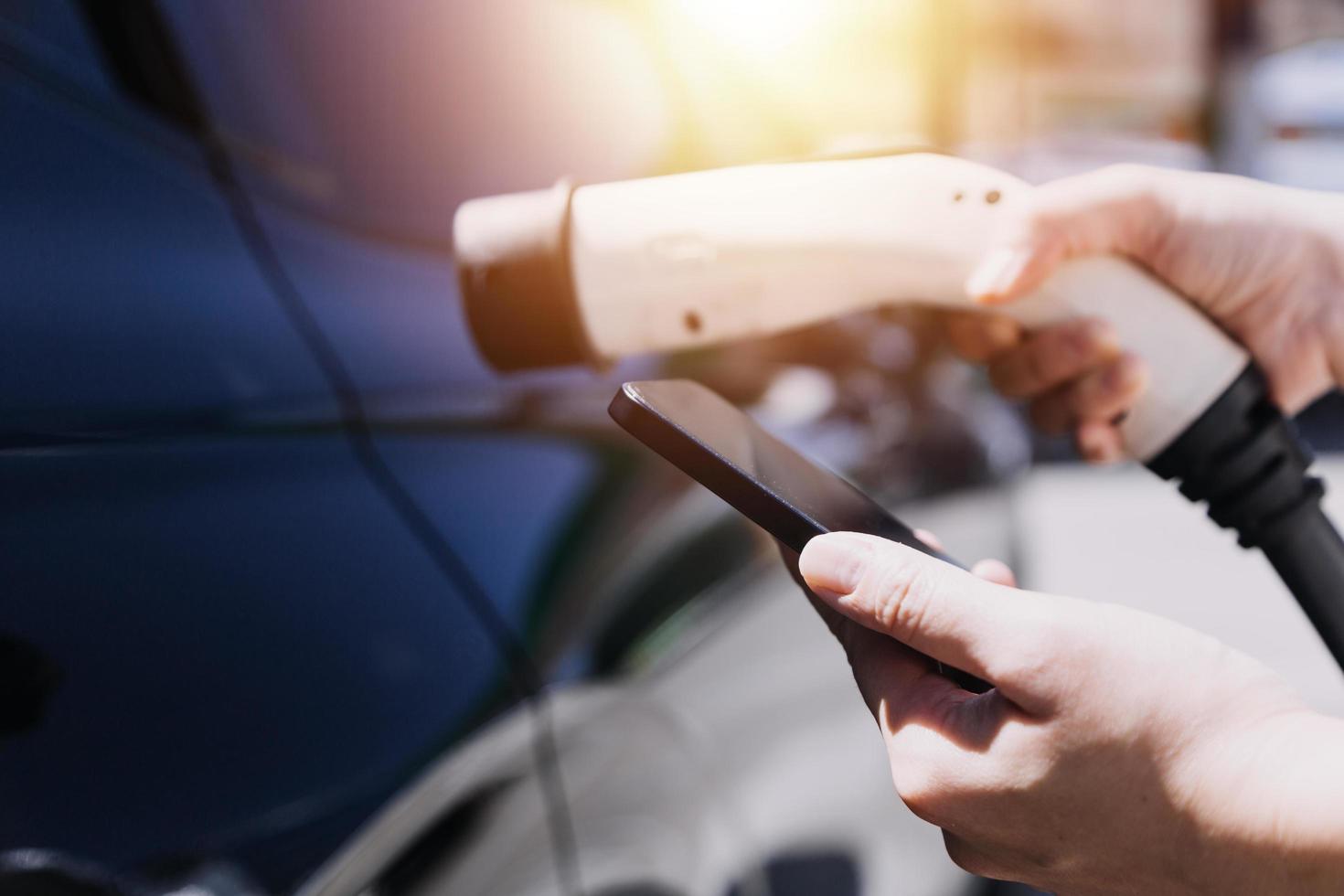 Hand plugging in a charger in an electric car socket.Electric car or ev is charging at station photo