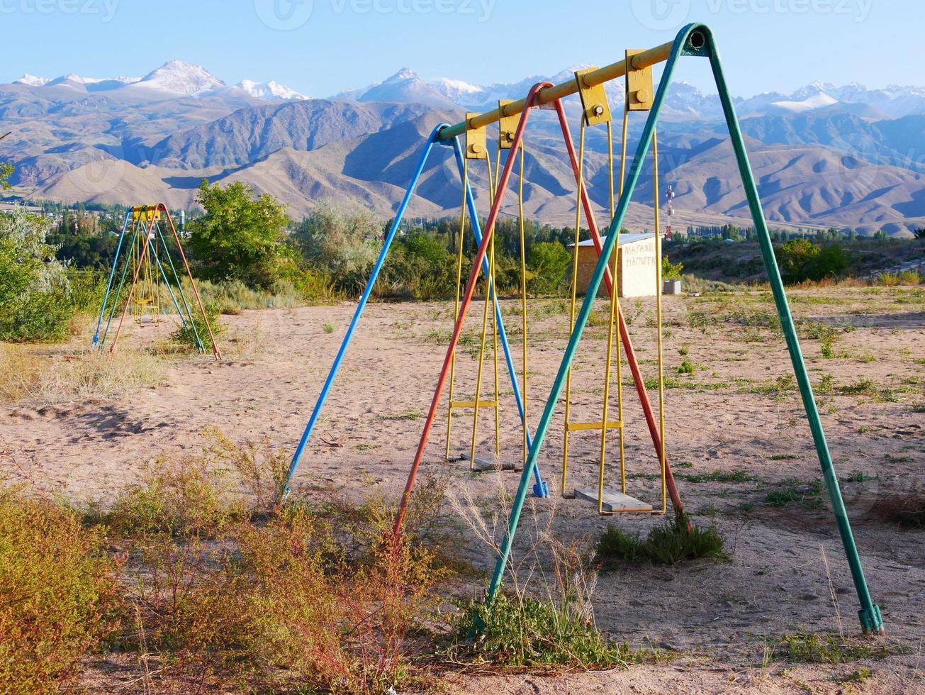 On an empty playground in Cholpon Ata, Kyrgyzstan, with mountains in the background photo