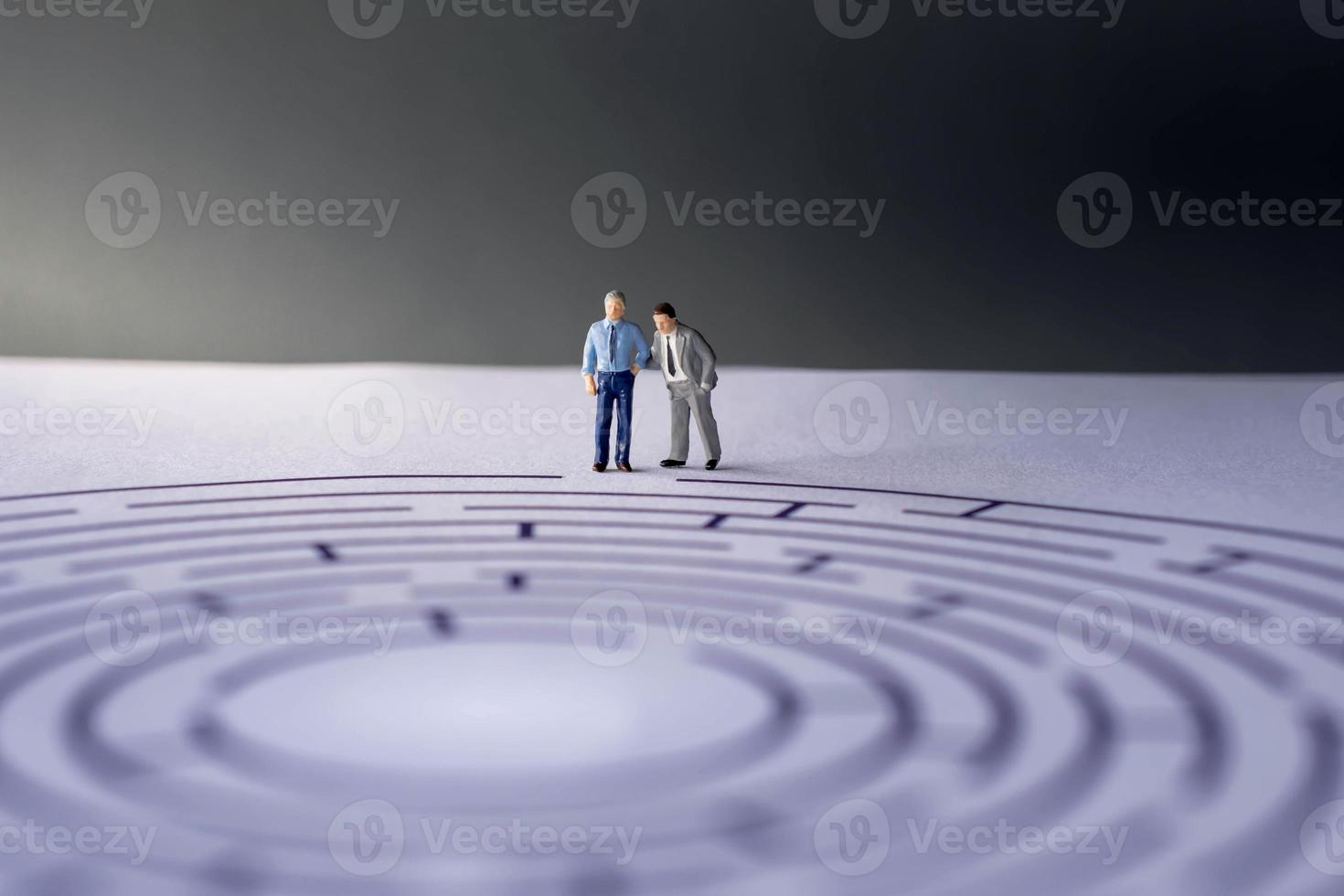 Challenge and Success Concept. present by two Miniature Figure of Businessman standing on the Maze Paper. one of them act like a Coach or Boss photo